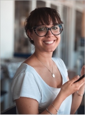 Woman with glasses smiling and holding cell phone