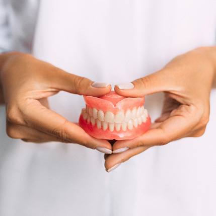 A dentist holding a pair of dentures