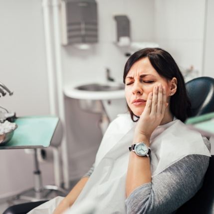 Dental patient holding the side of her cheek in pain