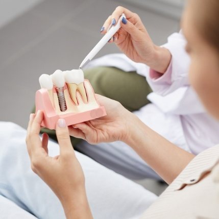 Dentist showing a patient a model of dental implants in Catonsville