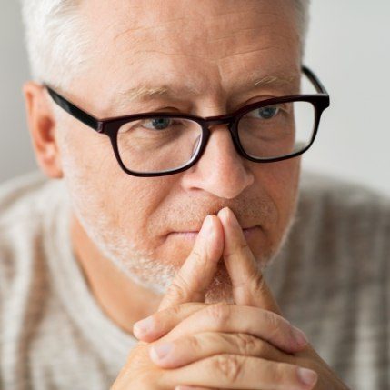 Senior man with glasses looking contemplative