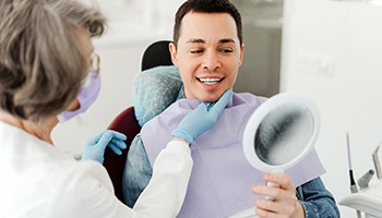 Man smiling at reflection in mirror with dentist