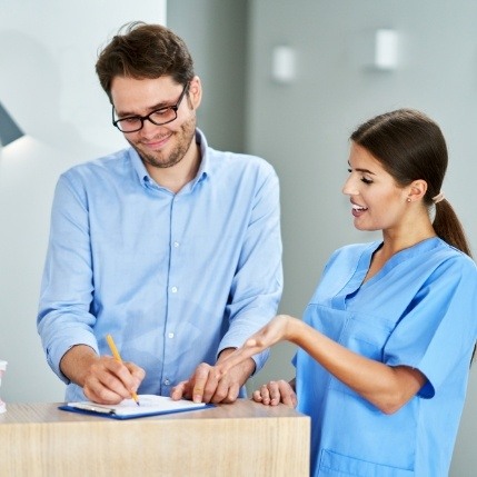 Dental team member showing patient where to sign on clipboard