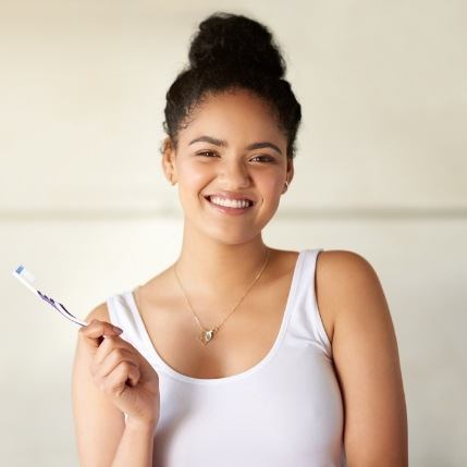 Smiling young woman holding toothbrush