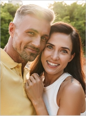 Man and woman smiling outdoors in late afternoon sun