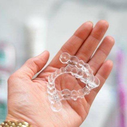 Hand holding two Invisalign clear aligners in Catonsville