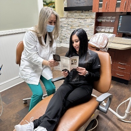 Doctor Bemani showing a pamphlet to a patient in the dental chair