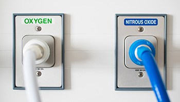 Oxygen and nitrous oxide tubes attached to wall