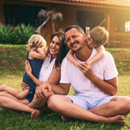 Smiling family of four sitting in their front yard