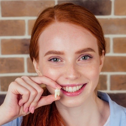 Woman holding her tooth after tooth extractions