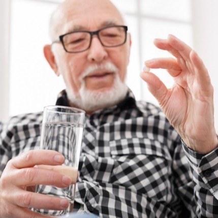 Senior man holding pill and glass of water