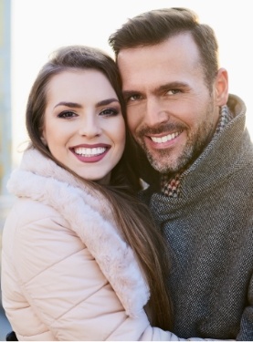 Man and woman in peacoats smiling outdoors