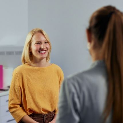 Woman in yellow sweater talking to dental team member