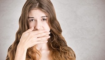 A woman covering her mouth because she’s embarrassed by the color of her teeth