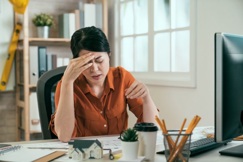 A working woman experiencing a TMJ headache