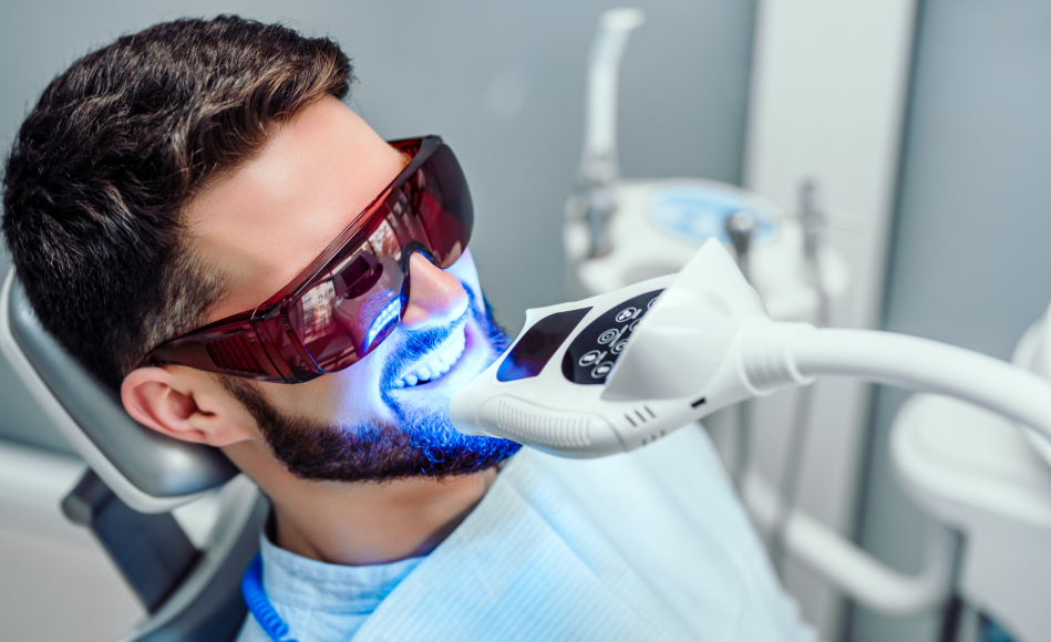 Man receiving dental teeth whitening treatment in chair